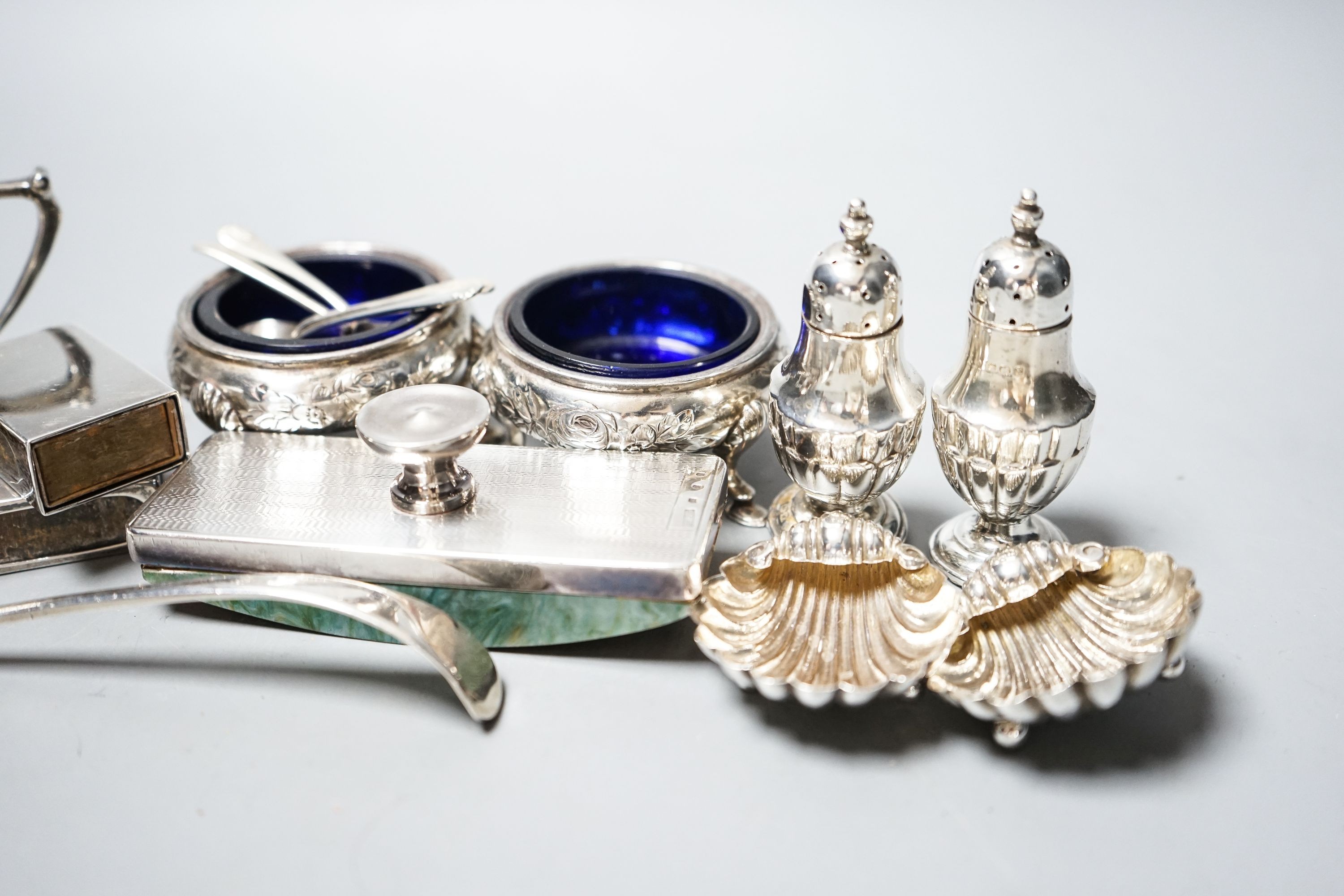 Small silver including a George V silver octagonal mustard, two Victorian bun salts, two shell salts, George III sifter spoon, two condiments, a blotter and two match box sleeves.
